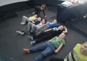 Dzieci leżą na macie w namiocie czekając na początek seansu